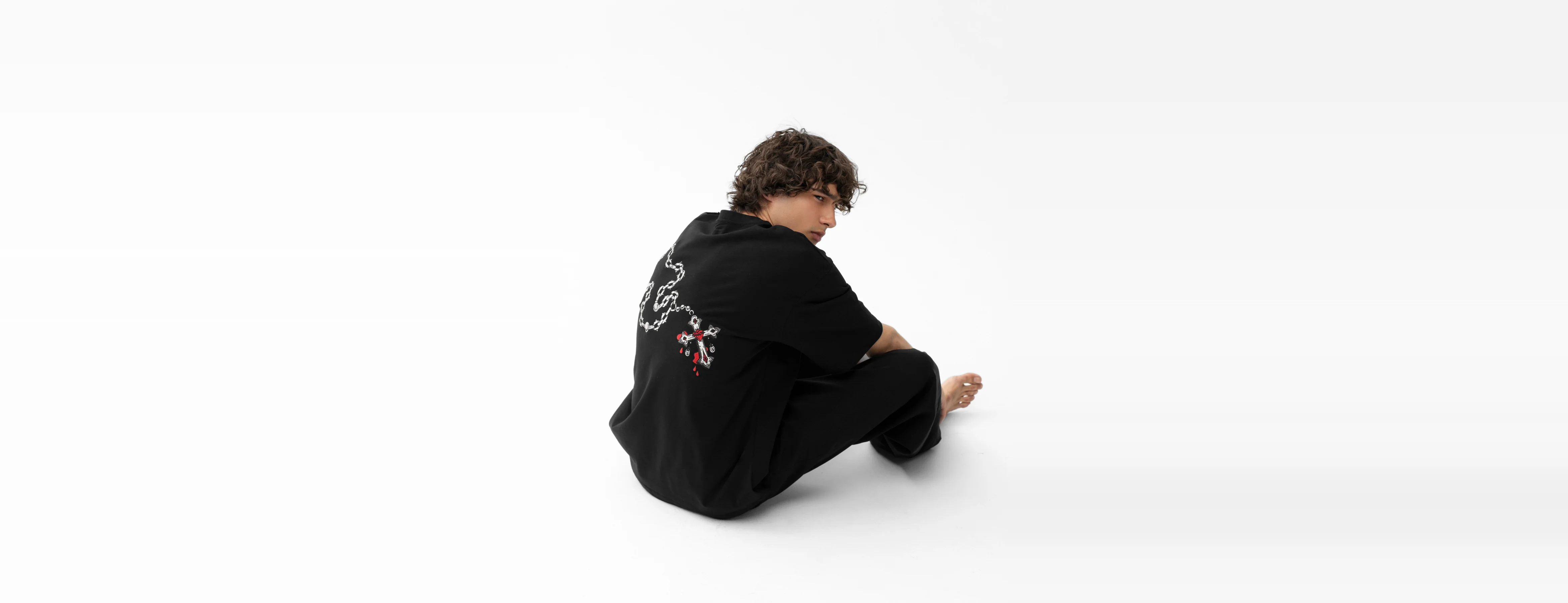 Skull and Roses apparel — seated model in the Sigil Cross tee